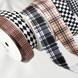May include: A collection of patterned ribbons in various designs, including plaid, houndstooth, and diamond patterns. The ribbons are in shades of brown, black, white, and beige, and are rolled on spools.