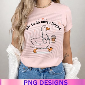 May include: A light pink short-sleeved t-shirt featuring a graphic of a white goose wearing a stethoscope and holding a coffee cup. The text "off to do nurse things" is printed in black above the goose, surrounded by thin, wavy black lines.