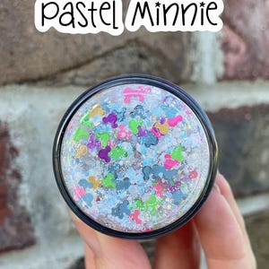 May include: A circular lid featuring a clear resin finish filled with multi-colored glitter and small mouse-ear shaped confetti in shades of pink, blue, green, and gold. The text "pastel Minnie" is printed in a black handwritten font above the lid.