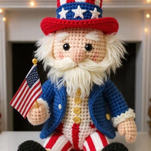May include: A crocheted Uncle Sam doll, featuring a red, white, and blue color scheme. The doll wears a top hat, a blue jacket, and red and white striped pants. It holds a small American flag and has a white beard.