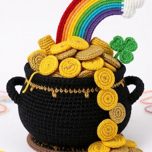 Può includere: Un vaso nero all'uncinetto traboccante di monete d'oro, un arcobaleno e un trifoglio verde. L'arcobaleno si inarca sopra il vaso, con strisce rosse, arancioni, gialle, verdi, blu e viola. Il vaso ha due manici e poggia su una base marrone.