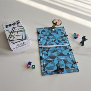 May include: A tabletop tennis board game titled Baseline, featuring a blue and black geometric patterned court, a white net, two player figures, six multi-coloured dice, and a circular token. The game box displays the title and court illustration.