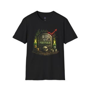 May include: Black t-shirt featuring a graphic design with a tombstone that reads "RIP MY PORTFOLIO." The design includes a skull, candles, and cryptocurrency symbols. A red arrow points upwards, suggesting market trends.