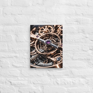 May include: Close-up of a canvas print featuring the intricate internal mechanism of a watch. The image showcases a complex arrangement of golden gears, silver components, and purple jewels. The canvas is mounted on a white brick wall.