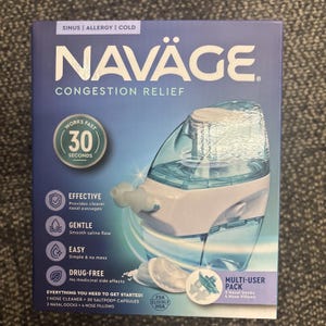 May include: A box for Naväge Congestion Relief, featuring a nasal cleaner and saltpod capsules. The box is blue and white, with the product name in large letters. Text on the box highlights features like effectiveness and drug-free. The product promises relief in 30 seconds.