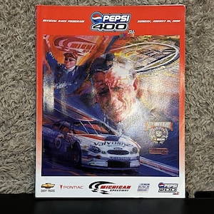 May include: An official race program for the Pepsi 400 on Sunday, August 16, 1998. The cover features a race car, a driver, and an aerial view of the Michigan Speedway. It includes the 50th Anniversary NASCAR logo and various sponsor branding.