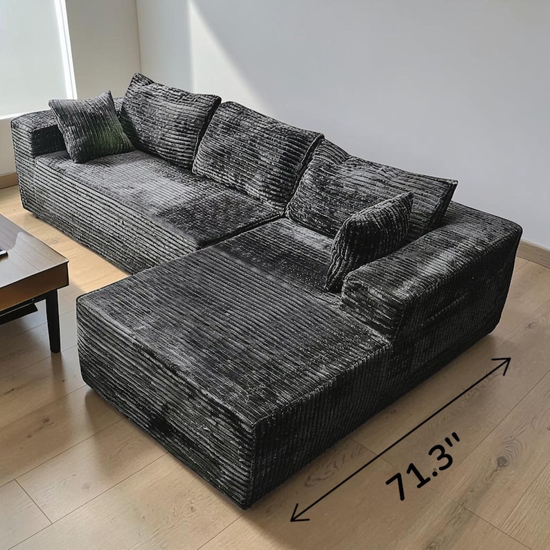 May include: A large, dark gray sectional sofa with a corduroy texture. The sofa has multiple cushions and a chaise lounge section, measuring 71.3 inches in length. The sofa is placed on a light-colored wooden floor.
