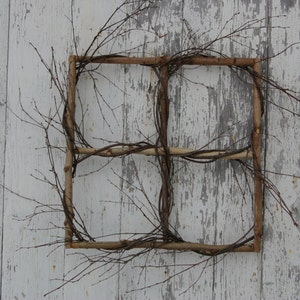 May include: A rustic window frame made of woven branches, with a weathered white wooden background.