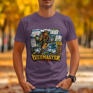 以下が含まれることがあります： ヘザーパープルのTシャツ。スカウトの制服を着たハイカーがGPSデバイスとノートパソコンを持っているグラフィックが描かれています。デザインには「Event Calendar」、「Data Trail」、そして下部に大きな黄色の文字で「Webmaster」というテキストが含まれています。