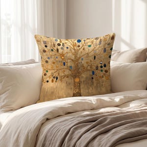 Peut inclure: Un coussin carré orné d'une illustration d'arbre aux tons dorés avec des branches tourbillonnantes complexes. Le motif comprend de petits accents circulaires et rectangulaires colorés dans des tons de bleu, noir et orange dispersés dans la canopée dorée.