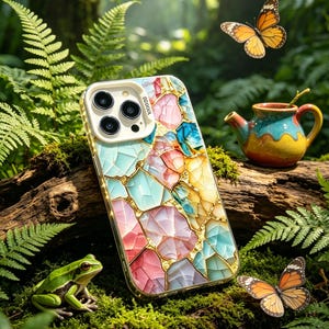 May include: A colorful phone case with a mosaic design in shades of pink, blue, yellow, and gold. The case is set against a backdrop of lush green foliage, with a small frog, butterflies, and a decorative teapot.