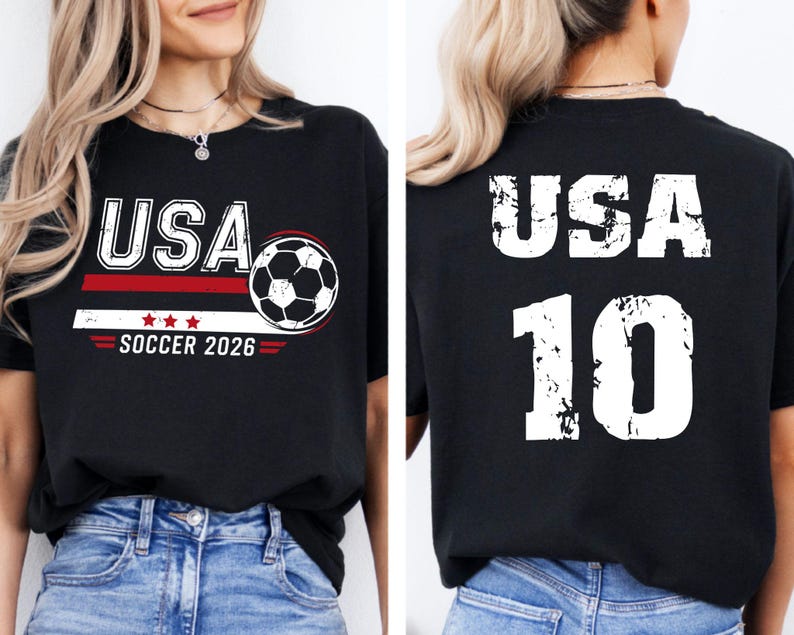 K&ouml;nnte beinhalten: Schwarzes T-Shirt mit "USA" in wei&szlig;en Buchstaben, einer Fu&szlig;ballgrafik und "SOCCER 2026" in Rot und Wei&szlig;. Auf der R&uuml;ckseite des Shirts stehen "USA" und die Nummer "10" in Wei&szlig;.