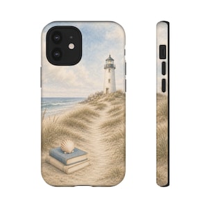 Puede incluir: Una funda para teléfono con una ilustración costera de un faro blanco en una duna cubierta de hierba frente al océano. En primer plano, dos libros apilados con una concha encima descansan en un sendero de arena hacia el faro.
