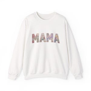Può includere: Una felpa bianca con la scritta "MAMA" in stampa floreale colorata sul petto. Il top a girocollo a maniche lunghe è uno stile casual, adatto all'uso quotidiano.
