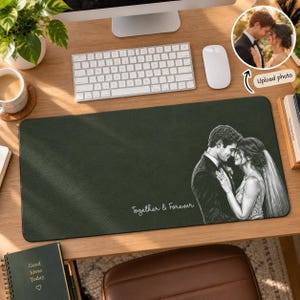 May include: A dark green rectangular desk mat featuring a white line-art illustration of a couple in wedding attire, with the text "Together & Forever" printed in white script. The mat has a textured surface and is placed on a wooden desk.