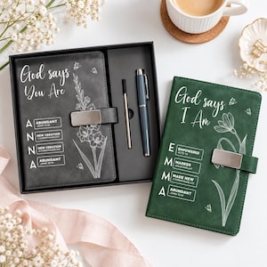May include: A black journal with a silver magnetic clasp, a pen, and a refill in a gift box, alongside a green journal with a silver magnetic clasp. Both journals feature white floral line art, butterflies, and the text God says You Are and God says I Am with personalized names and Bible verses.