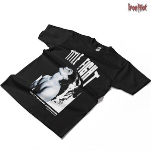 Puede incluir: Camiseta negra con una imagen en blanco y negro de una persona y las palabras "TITLE FIGHT" en blanco. El texto "LIVE AT THE VELVET UNDERGROUND" est&aacute; debajo de la imagen. El logotipo de Iron Riot est&aacute; en la esquina superior derecha.
