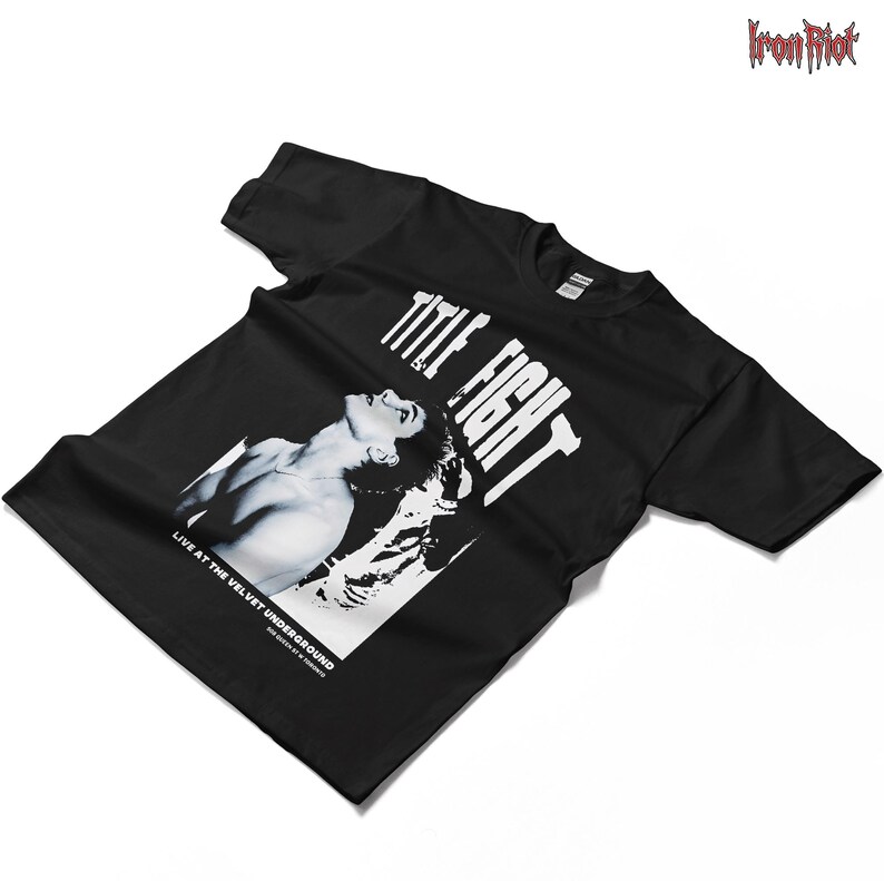 Puede incluir: Camiseta negra con una imagen en blanco y negro de una persona y las palabras "TITLE FIGHT" en blanco. El texto "LIVE AT THE VELVET UNDERGROUND" est&aacute; debajo de la imagen. El logotipo de Iron Riot est&aacute; en la esquina superior derecha.