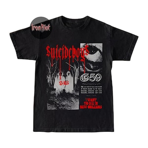 Puede incluir: Camiseta negra con el nombre de la banda "Suicideboys" en letras góticas rojas. El diseño incluye dos figuras con túnicas blancas, el número "659" y el texto "I WANT TO DIE IN NEW ORLEANS".