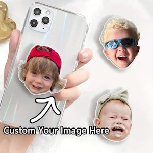 May include: Clear phone case with a custom image pop-socket featuring a child wearing a red cap. Additional custom image stickers of children are also visible. The text "Custom Your Image Here" is displayed on the phone case.