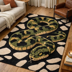 Può includere: Tappeto nero con un grande disegno di serpente in verde, giallo e nero. Il serpente è arrotolato e dettagliato, su uno sfondo color crema con forme bianche irregolari. Il tappeto è in un soggiorno.