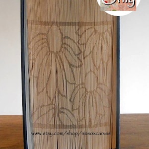 May include: A book with pages cut and folded to create a 3D design of a floral pattern. The book is standing upright on a wooden surface. The text "Pattern Only" is visible in the upper right corner of the image. The text "www.etsy.com/shop/nosoxcarves" is visible at the bottom of the book.