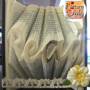 May include: A book art sculpture with the word "remarkable" folded into the pages. The book is decorated with lace and a yellow flower.