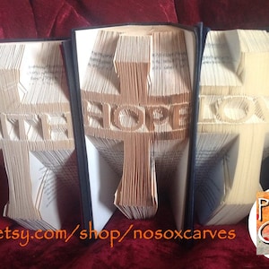 May include: Three book folding patterns for a cross with the words "Faith", "Hope", and "Love" on each. The patterns are displayed in a row on a red surface. The text "Pattern Only" is visible in the lower right corner of the image.