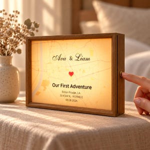 May include: A rectangular wooden light box featuring a backlit map design with the names Ava & Liam, a red heart icon, the text Our First Adventure, Baton Rouge, LA, coordinates 30.4344 N, -91.0940 E, and the date 08.08.2026.
