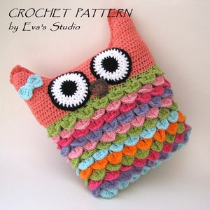Puede incluir: Una almohada de b&uacute;ho de crochet con un esquema de color rosa, verde, morado, azul y naranja. El b&uacute;ho tiene grandes ojos negros con pupilas blancas y una nariz marr&oacute;n.