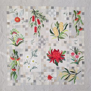 May include: A square quilt featuring a light gray background with a grid of small squares. The quilt displays various botanical illustrations including red bottlebrush, yellow banksia, white daisies, a large red waratah, and green eucalyptus leaves.