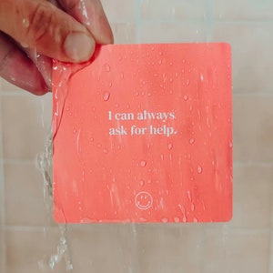May include: A pink affirmation card with the text "I can always ask for help." and a smiley face icon.