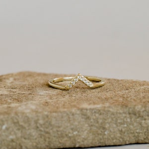 Puede incluir: Un anillo de oro con un dise&ntilde;o de chevron engastado con peque&ntilde;as piedras transparentes.