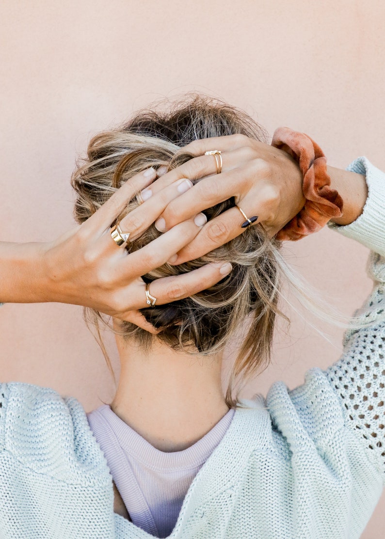 Puede incluir: Una mujer con cabello rubio que lleva un su&eacute;ter azul claro y varios anillos de oro en los dedos.