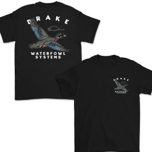 May include: Black t-shirts with a waterfowl graphic. One shirt features a large flying duck design with the word "DRAKE" above and "WATERFOWL SYSTEMS" below. The other shirt has a smaller version of the same design on the chest.