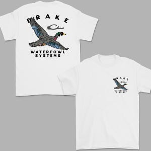 May include: White t-shirts with a graphic of a flying duck. The back of the shirt has a large duck graphic with the word "DRAKE" above it and "WATERFOWL SYSTEMS" below. The front of the shirt has a smaller version of the same graphic.
