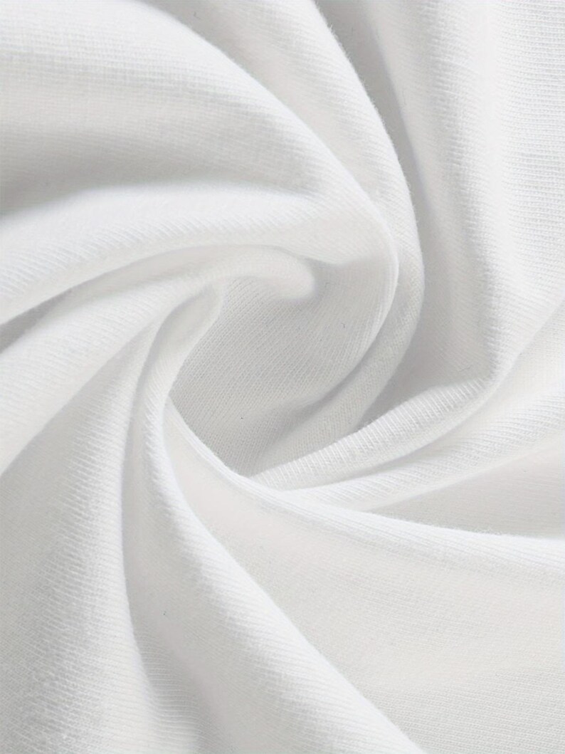 May include: Close-up of white fabric with soft folds and subtle texture. The fabric appears to be a knit or jersey material, with a smooth surface and gentle shadows. The image highlights the fabric's drape and the play of light.