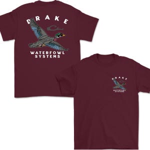 May include: Maroon t-shirts with a graphic of a duck in flight, wearing sunglasses. The word "DRAKE" is arched above the duck, and "WATERFOWL SYSTEMS" is below. One shirt has the graphic on the back, and the other on the front.