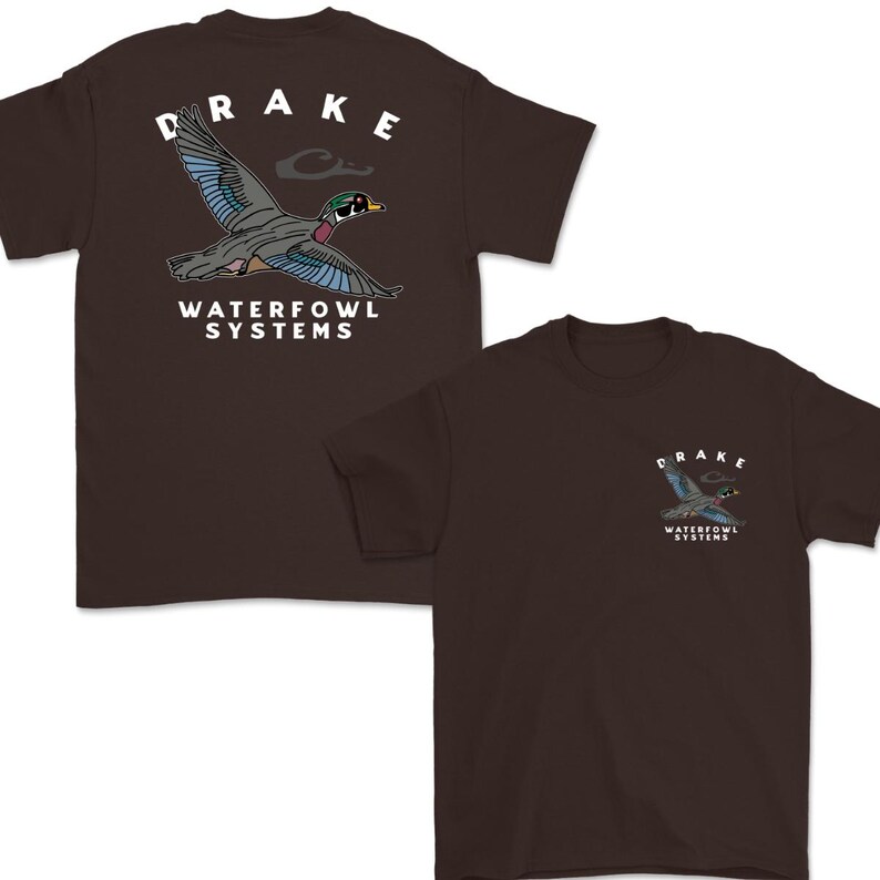 May include: Two brown t-shirts with a graphic of a duck in flight. The word "DRAKE" is above the duck, and "WATERFOWL SYSTEMS" is below it. The second shirt has a smaller version of the graphic on the chest.