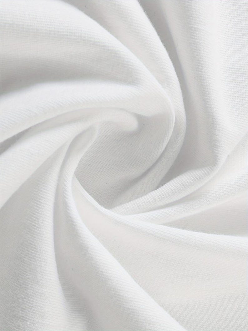 May include: Close-up of white fabric with soft folds and subtle textures. The fabric appears to be a knit or woven material, with visible threads and a smooth surface. The lighting highlights the curves and shadows of the folds.