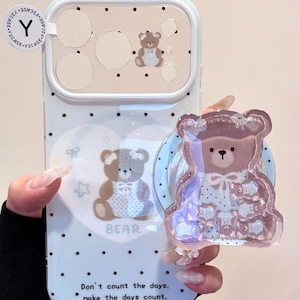 May include: A light blue phone case with a bear design and a matching pop socket. The case has a bear illustration, polka dots, and the text "Don't count the days, make the days count."