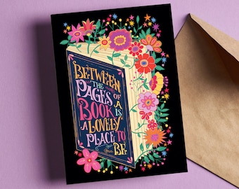 May include: A black card with a colourful illustration of an open book with the text "Between the pages of a book is a lovely place to be."  The book is surrounded by flowers and stars.