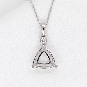 May include: A silver pendant necklace with a triangular design. The pendant features a small, round gemstone above the triangle and is suspended from a delicate chain. The necklace is displayed on a white surface.