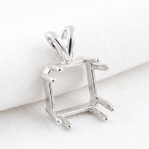 以下が含まれることがあります： 正方形のフレームと上部にループが付いた、銀色のペンダントセッティング。セッティングには、宝石を保持するための4つの爪があります。ペンダントは、ジュエリー作りのために設計されています。