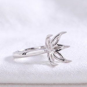 May include: A polished silver-toned metal ring setting featuring a multi-pronged head designed to hold a gemstone. The prongs are shaped like elongated petals, extending upward from the band to create a secure, open-work basket structure.