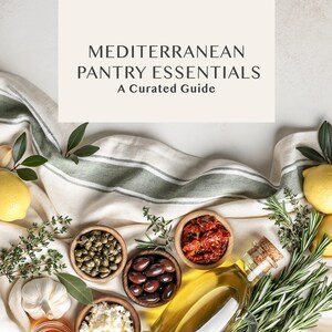 May include: A flat lay image featuring a variety of Mediterranean pantry essentials. The image includes small wooden bowls filled with olives, capers, and sun-dried tomatoes. A bottle of olive oil, lemons, garlic, and herbs are also present, with the text "MEDITERRANEAN PANTRY ESSENTIALS A Curated Guide".