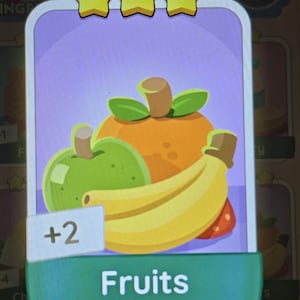 May include: A digital game card featuring a cartoon illustration of a green apple, an orange, and a yellow banana. The card has three yellow stars at the top, a light purple background, and a teal banner at the bottom with the text Fruits and a +2 label.