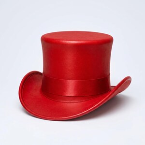 May include: A vibrant red top hat featuring a smooth, matte finish on the crown and brim. The hat includes a matching red satin ribbon band wrapped around the base of the crown, creating a uniform monochromatic appearance with a structured shape.