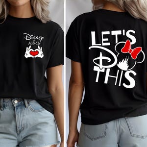 K&ouml;nnte beinhalten: Schwarzes T-Shirt mit wei&szlig;em Text und Grafiken. Auf der Vorderseite steht "Disney vibes" mit Mickey Mouse-H&auml;nden, die ein Herz bilden. Auf der R&uuml;ckseite steht "Let's Do This" mit einer Minnie Mouse-Grafik und roter Schleife.