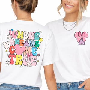May include: White t-shirts with colourful graphics. One shirt features the text "WHERE DREAMS COME TRUE" with Mickey Mouse ears and stars. The other shirt has a Minnie Mouse head with a castle design.